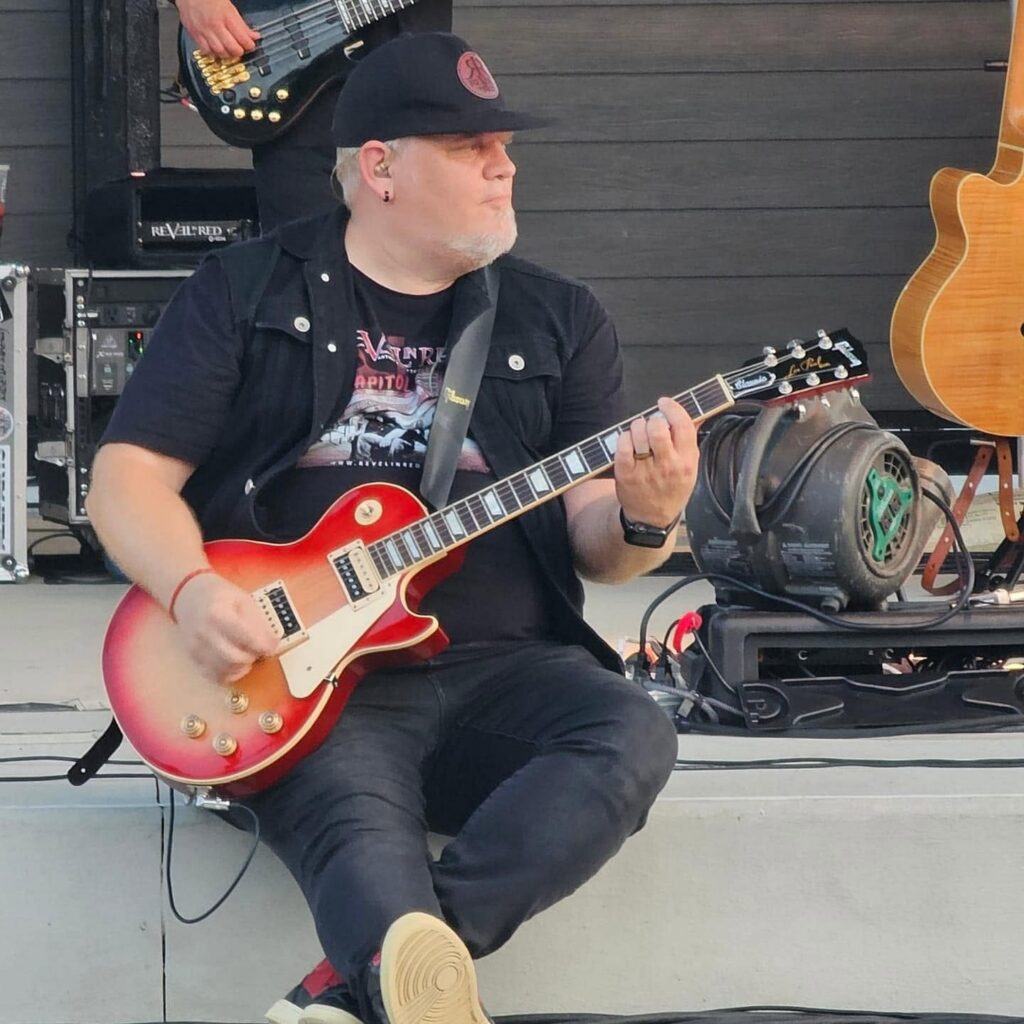 Brian Carroll sitting with a guitar in his hands